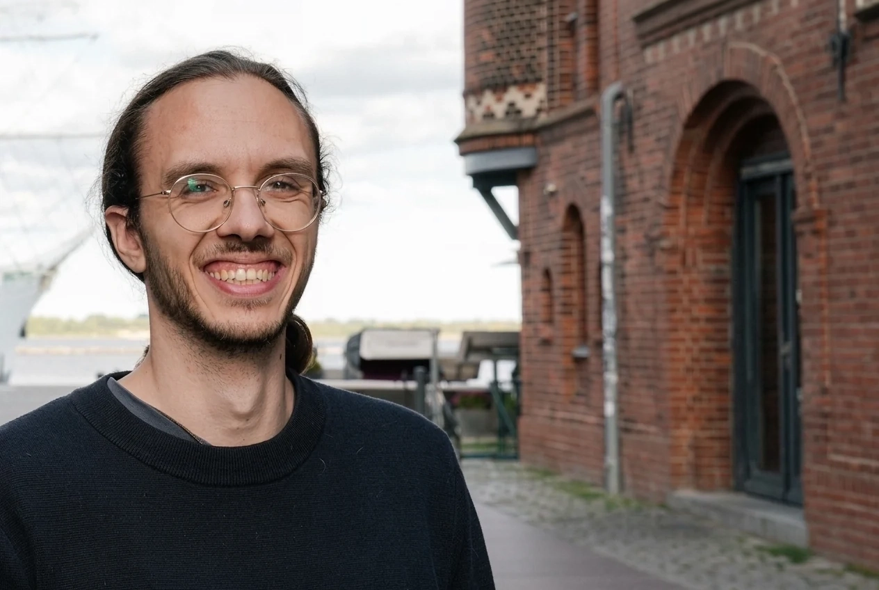 Porträt von Tom, Marketing-Berater bei Talentküste, in einer historischen Gasse in Stralsund an der Ostseeküste.